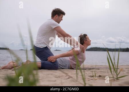 Homme aidant la femme à faire le yoga bhujangasana cobra pose Banque D'Images