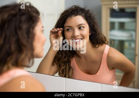 Belle femme l'Épilation sourcils dans une salle de bains privative. Banque D'Images