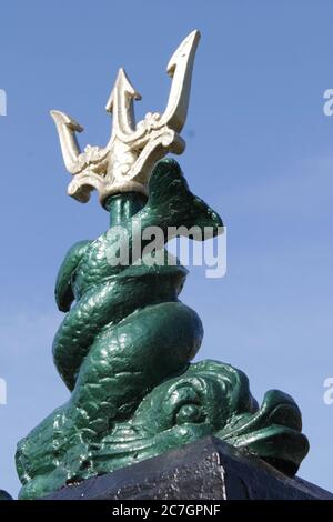 Prise de vue verticale à angle bas d'un trident enveloppé dans un statue de poisson sur fond bleu clair Banque D'Images