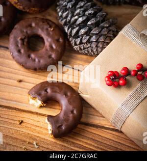 Gros plan à angle élevé d'un donut de chocolat à moitié mangé à un cadeau emballé et un cône de pin Banque D'Images