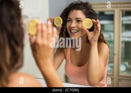 Belle femme tenant des tranches de citron dans la salle de bains. Banque D'Images