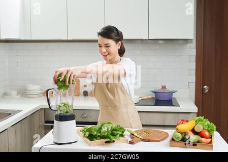 femme de ménage cuisant un smoothie de détox sain avec des fruits frais et des légumes verts Banque D'Images