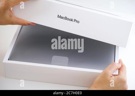 Tambov, Fédération de Russie - 09 juillet 2020 une femme ouvre la boîte avec MacBook Pro. Prise de vue en studio. Banque D'Images