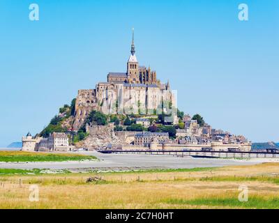 Les gens marchent le long d'une chaussée pour atteindre l'historique Mont-Saint-Michel, Normandie, France, par une journée d'été lumineuse. Banque D'Images