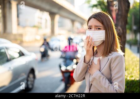 Jeune femme d'affaires portant un masque chirurgical et coulant tout en marchant en public dans une situation de propagation du coronavirus ou du COVID-19 Banque D'Images