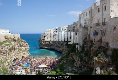 Polignano a Mare, Italie - 15 août 2014: Les gens se détendent et nagent sur la belle plage Lama Monachile. Crique de galets blanche entre murs rocheux et chauve-souris Banque D'Images