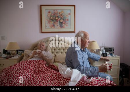 Un couple âgé dans les années 80 s'est assis sur le lit dans son pyjama avant de se lever dans le matin, Angleterre, Royaume-Uni Banque D'Images
