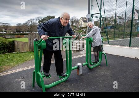 Couple âgé dans les années 80 dans un parc d'exercice essayant l'appareil ensemble, Kingsbridge, Devon, Angleterre, Royaume-Uni Banque D'Images