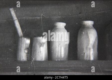 Belle photographie en noir et blanc vintage des années 1970 d'une vie de bouteilles dans une cabane en rondins de campagne. Banque D'Images