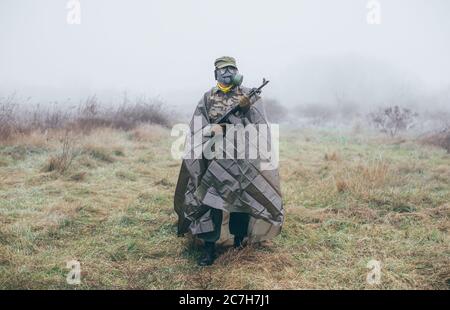 soldat avec mitrailleuse portant un masque à gaz et un costume de protection contre les armes chimiques Banque D'Images