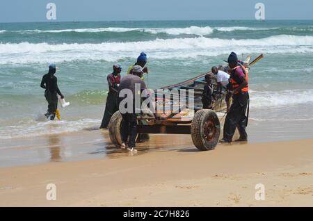 Pêcheurs artisanaux poussant les pirogues hors de l'eau à Lompoul, Sénégal Banque D'Images