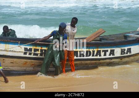 Pêcheurs artisanaux poussant les pirogues hors de l'eau à Lompoul, Sénégal Banque D'Images