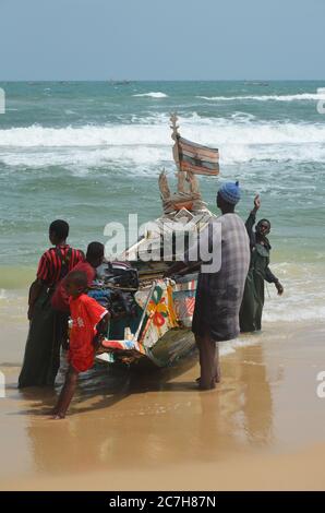 Pêcheurs artisanaux poussant les pirogues hors de l'eau à Lompoul, Sénégal Banque D'Images