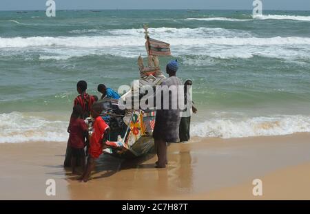 Pêcheurs artisanaux poussant les pirogues hors de l'eau à Lompoul, Sénégal Banque D'Images