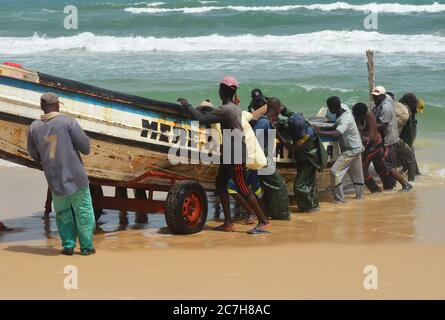 Pêcheurs artisanaux poussant les pirogues hors de l'eau à Lompoul, Sénégal Banque D'Images