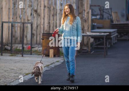 jeune femme marchant son chien dans la rue Banque D'Images