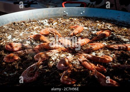 femme préparant une fideuá espagnole avec des crevettes et des nouilles calmars dans un moule à paella Banque D'Images