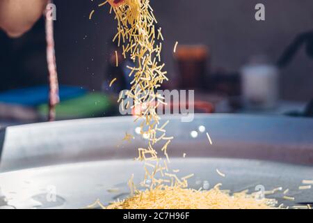 femme préparant une fideuá espagnole avec des crevettes et des nouilles calmars dans un moule à paella Banque D'Images