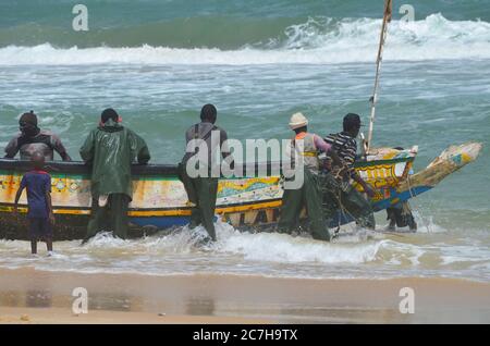 Pêcheurs artisanaux poussant les pirogues hors de l'eau à Lompoul, Sénégal Banque D'Images