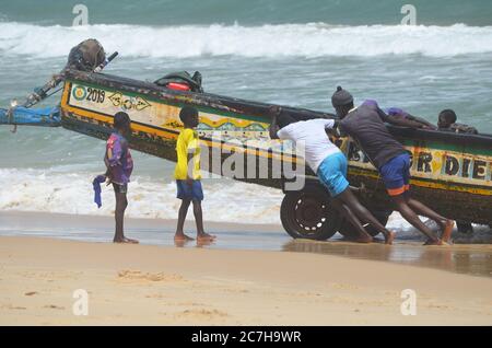 Pêcheurs artisanaux poussant les pirogues hors de l'eau à Lompoul, Sénégal Banque D'Images