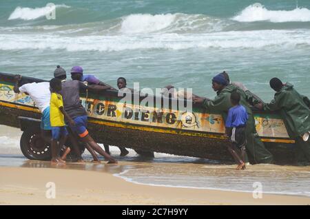 Pêcheurs artisanaux poussant les pirogues hors de l'eau à Lompoul, Sénégal Banque D'Images