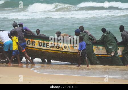 Pêcheurs artisanaux poussant les pirogues hors de l'eau à Lompoul, Sénégal Banque D'Images