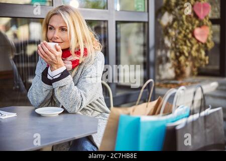 Femme mûre et attentionnés avec des sacs de shopping assis dans le café Banque D'Images