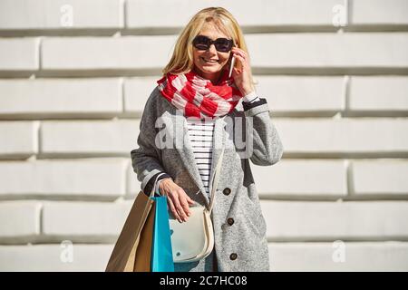 Bonne femme caucasienne souriante avec des sacs de shopping dans la rue Banque D'Images