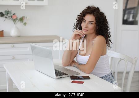 Jeune femme travaillant à la maison avec un ordinateur portable regardant dans l'appareil photo Banque D'Images