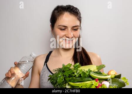La fille tient une bouteille d'eau et une assiette avec des légumes verts dans ses mains. Une bonne nutrition, des légumes dans le régime, le régime de céto, le corps détox Banque D'Images