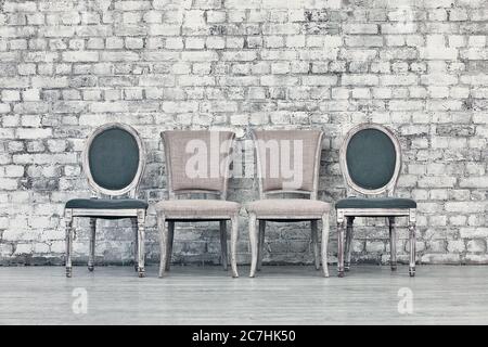 différentes chaises dans une ligne contre un mur de brique blanche Banque D'Images
