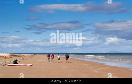 PLAGE DE LOSSIEMOUTH ET CÔTE DE LA MER MORAY EN ÉCOSSE EN ÉTÉ, RANDONNEURS ET PADDLE BOARD SUR LA PLAGE Banque D'Images