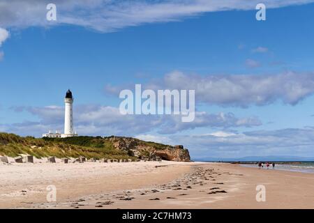 PLAGE DE LOSSIEMOUTH ET CÔTE DE LA MER MORAY EN ÉCOSSE EN ÉTÉ AVEC LE PHARE DE COVESEA ET LES RANDONNEURS RANDONNÉE SUR LA PLAGE Banque D'Images