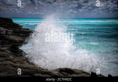 Une vague qui s'est écrasante frappe des rochers sur la plage de Horseshoe Bay Beach, Bermudes Banque D'Images