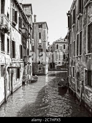 Plan vertical à haut angle en niveaux de gris d'un canal dans le quartier historique de Venise, Italie Banque D'Images