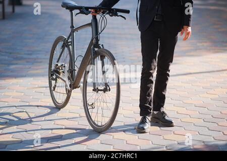 Homme en costume tenant un vélo de banlieue. Vélo dans la ville, travail à vélo Banque D'Images