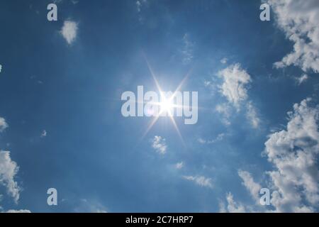 Rayons du soleil brillant dans le ciel sombre avec quelques nuages Banque D'Images