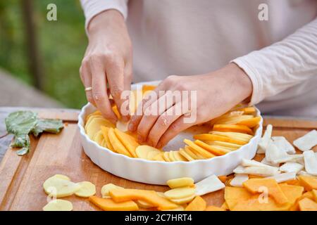 Préparez un gratin de pommes de terre, de citrouille et d'artichaut de Jérusalem, disposez les ingrédients en tranches dans une poêle à pain beurrée Banque D'Images