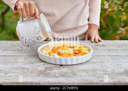 Préparez un gratin de pommes de terre, d'artichauts de citrouille et de Jérusalem, versez les ingrédients en tranches dans un moule beurré avec du lait et de la crème dans un pot Banque D'Images