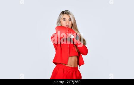 Le sport est notre vie. Belle femme avec des gants de boxe rouges. Jeune femme sportive en combinaison et gants de boxe. Blonde boxer femme. Coup de pied. Confiante jeune sportswoman posant dans des gants de boxe. Banque D'Images