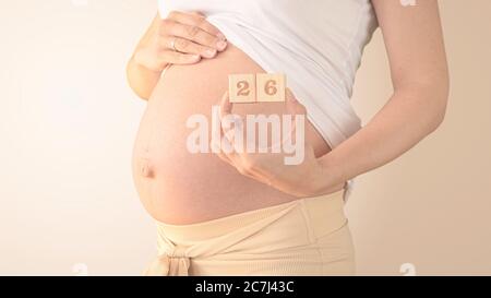 Jeune femme enceinte avec numéro de semaine de grossesse à côté de son ventre. Photos de la croissance du ventre à 26 semaines de grossesse. Alimentation saine pendant la grossesse Banque D'Images