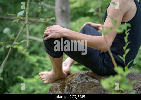 Partie basse de l'homme assis sur la roche dans la forêt Banque D'Images