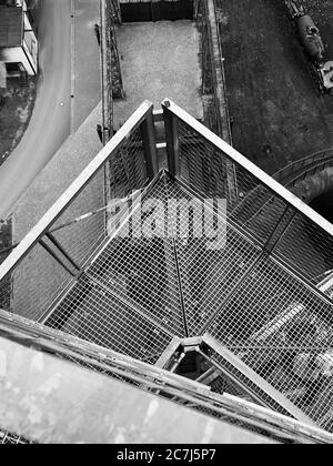 Prise de vue verticale en niveaux de gris à grand angle de l'escalier en fer à l'extérieur le bâtiment Banque D'Images