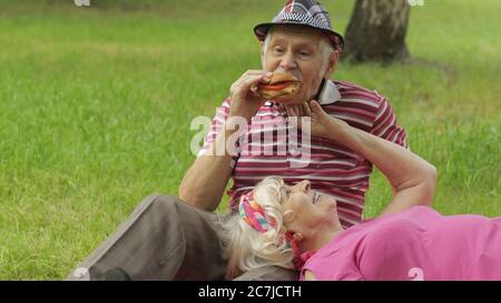 Pique-nique familial dans le parc. Les personnes âgées, les couples actifs de race blanche s'assoient sur une couverture et boivent du vin. Parler et célébrer l'anniversaire. Homme âgé, femme. Mari, femme. Grand-père, grand-mère Banque D'Images