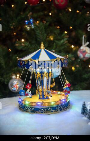 Photo verticale d'un ornement de carrousel d'enfant avec le décoré Arbre de Noël en arrière-plan Banque D'Images