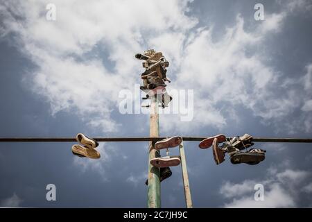 Photo à angle bas de chaussures pendues sur un tube de fer sous le ciel nuageux Banque D'Images