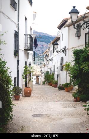 Allée avec pots de fleurs le long des maisons blanches avec vue sur les montagnes dans la vieille ville d'Altea, Costa Blanca, Espagne Banque D'Images