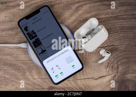 L'iPhone 11 Pro Max d'Apple se trouve sur le plateau de charge, l'écran affiche l'état de charge de l'AirPods Pro, la charge sans fil, Banque D'Images