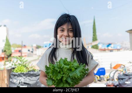 fille avec de la laitue sur ses mains dans un jardin urbain Banque D'Images