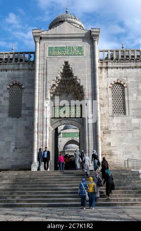 Les visiteurs de la Mosquée bleue dans le quartier Sultanahmet d'Istanbul en Turquie passent par la porte dans la cour. Banque D'Images